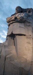 Martin Luther King Statue in stone. Vertical photo at dusk with lights lighting up MLK Jr.