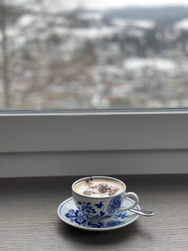 A cup of Coffee on a windows and spoon in it.