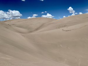 Sand dunes of the desert with clouds in the sky.
