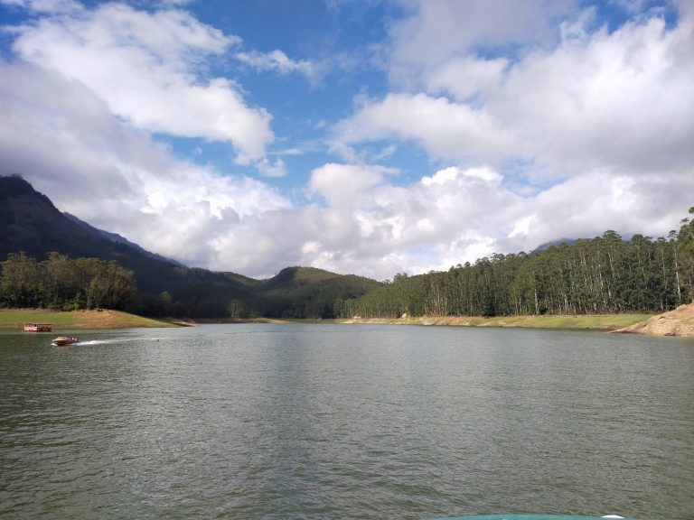 Two boats on the Mattupetti River boating area, flanked by trees and mountains.