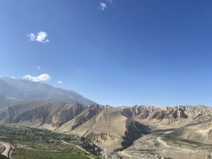 Upper Mustang Nepal: grey/brown mountains under a bright blue sky with a few wispy clouds.
