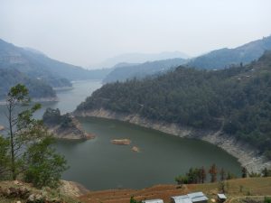 A lake in a valley between mountains. There are a few islands and many trees.