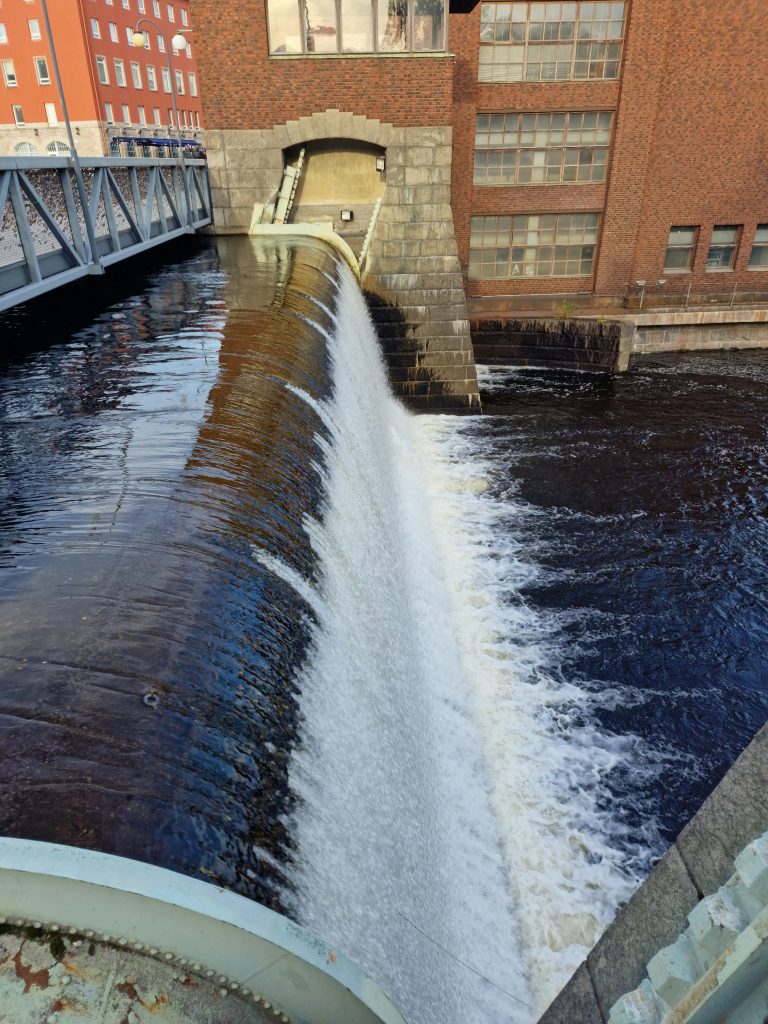 Small man made waterfall in Tampere city Finland, surrounded by brick and stone buildings