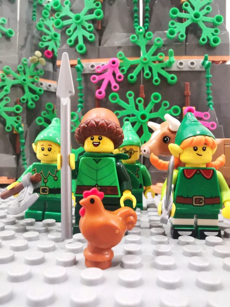 Miniature toy elf figures, a cow and a chicken fixed on a board, Lego style