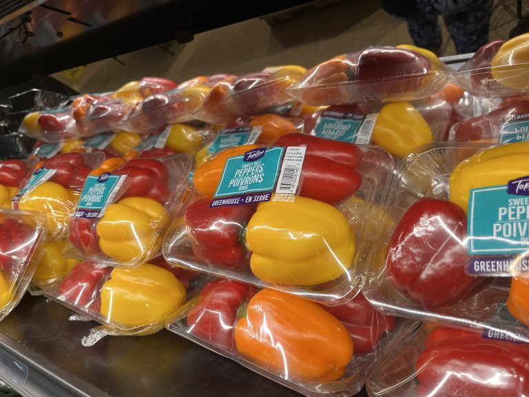 Capsicum, red, yellow, and orange peppers in plastic to be sold at a store.