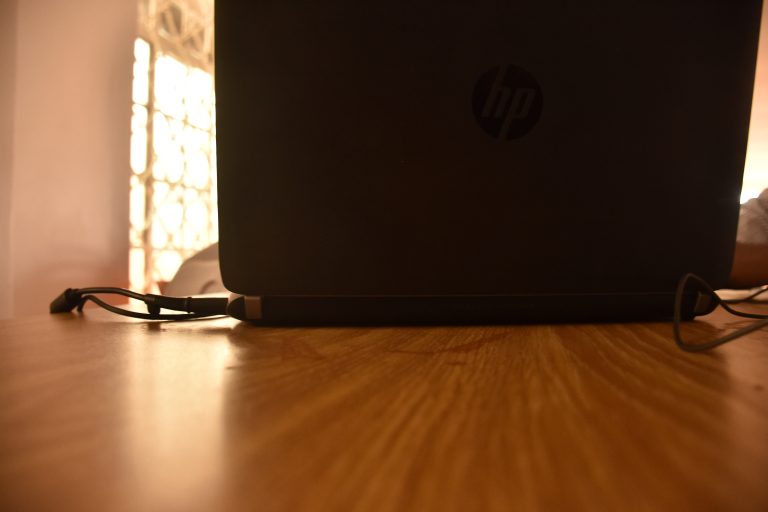 Backside of a laptop on a wooden table, camera right on the wood so there’s forced perspective.