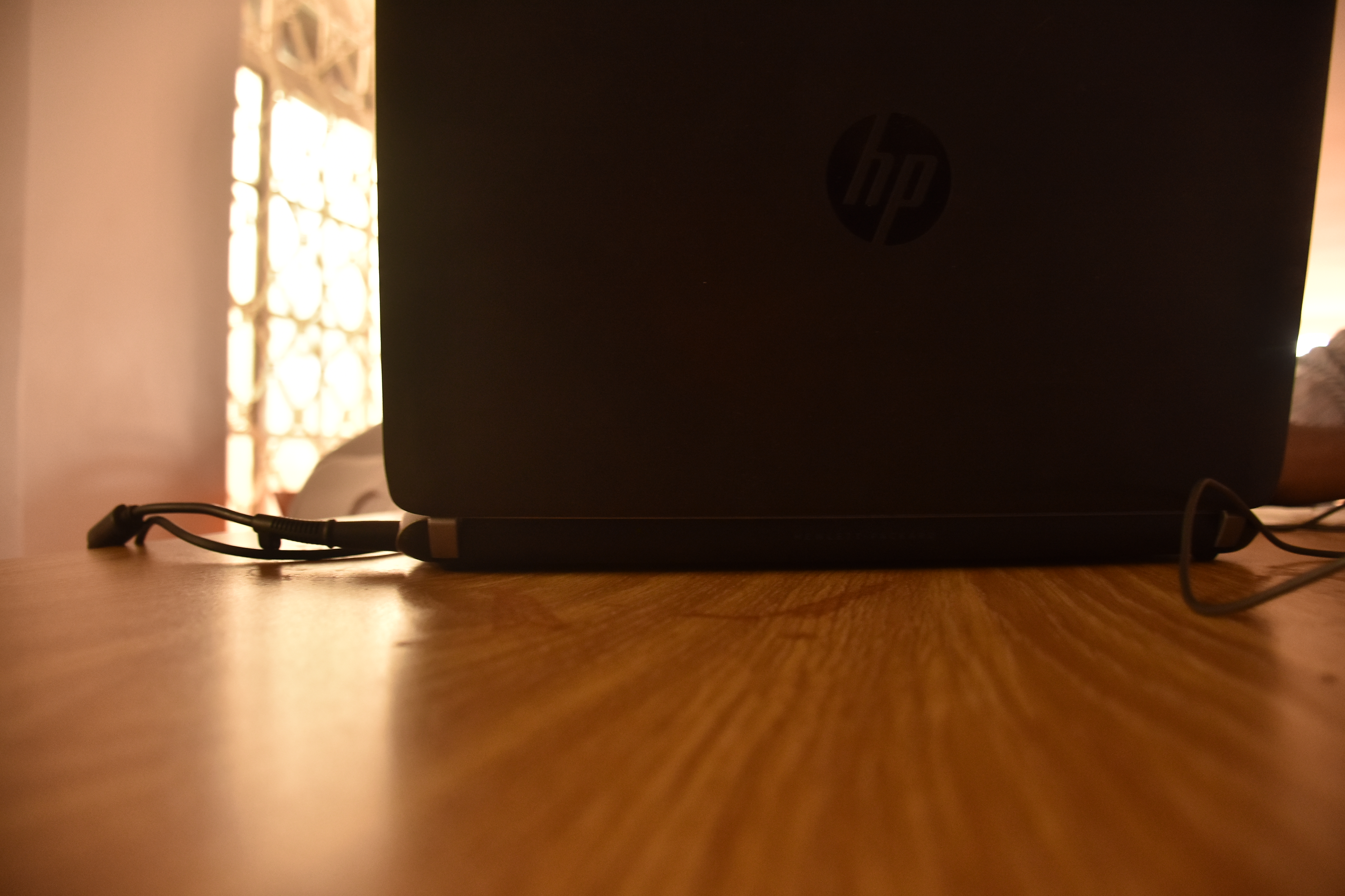 Backside of a laptop on a wooden table, camera right on the wood so there's forced perspective. 