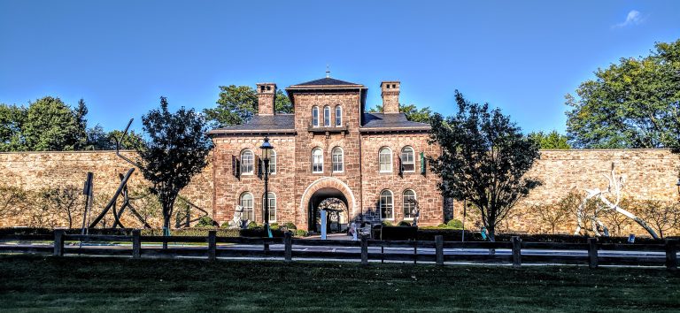 Old brick walled jail. Blue sunny day art work in front.