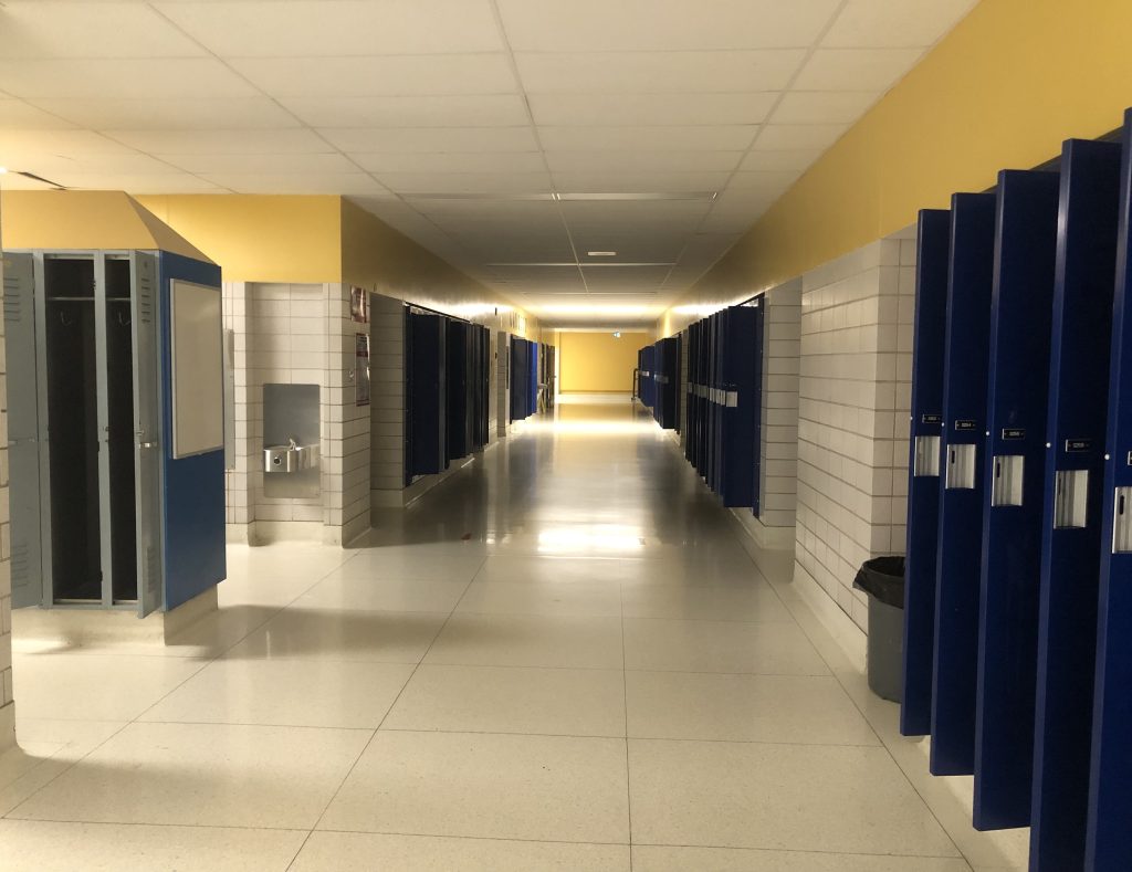 An empty school hallway with all the locker doors open after the last day of school.