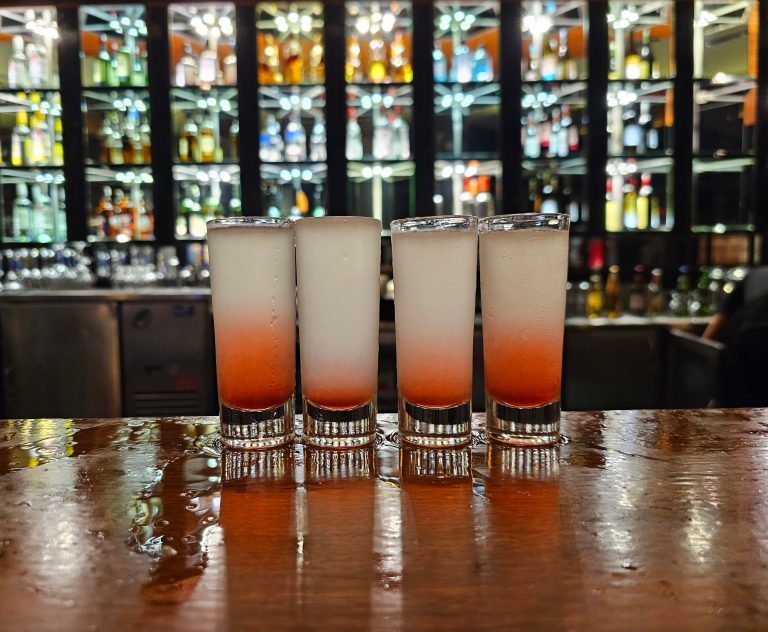 Picture of 4 glasses of shooters on a bar counter.