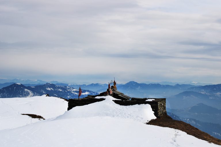 A view of mountains covered with snow and a sky covered with clouds.