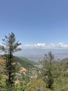 Kathmandu, viewed from Sangha, trees in the foreground, Bhaktapur city and mountain in the distance.