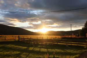 Sun dropping over the fields behind the mountain with a garden fence in the foreground