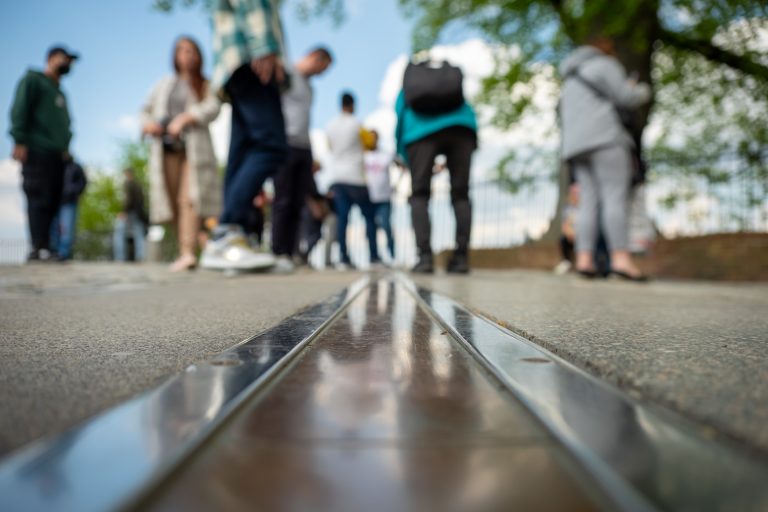 The Prime Meridian at Greenwich, shallow depth of field, with out-of-focus people in the background.