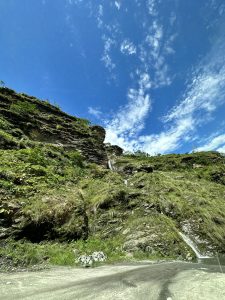 Waterfall cascading down a grassy hill on a bright blue sky day