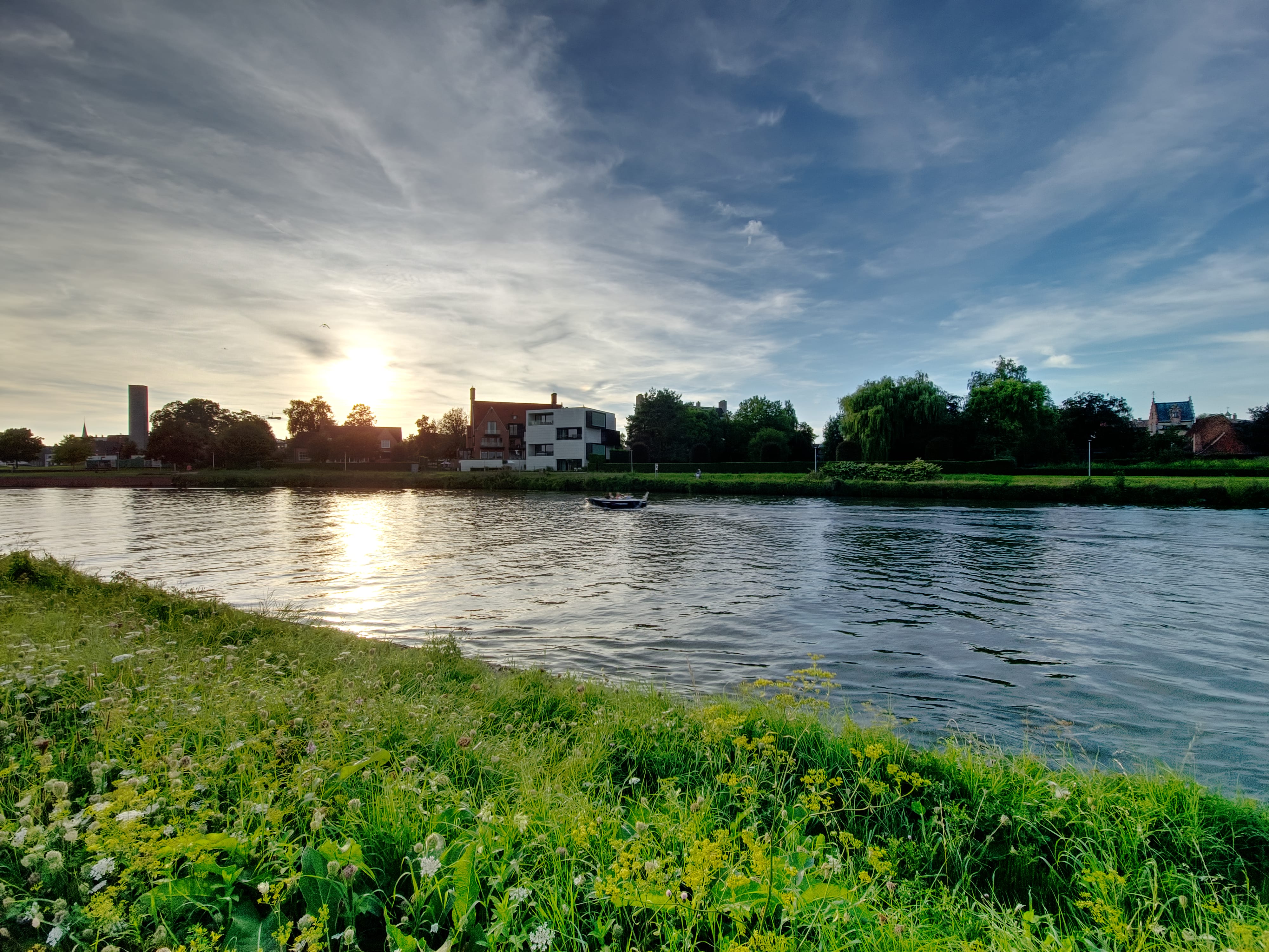 A sunset over the "Leie" canal with a little boat on the water.