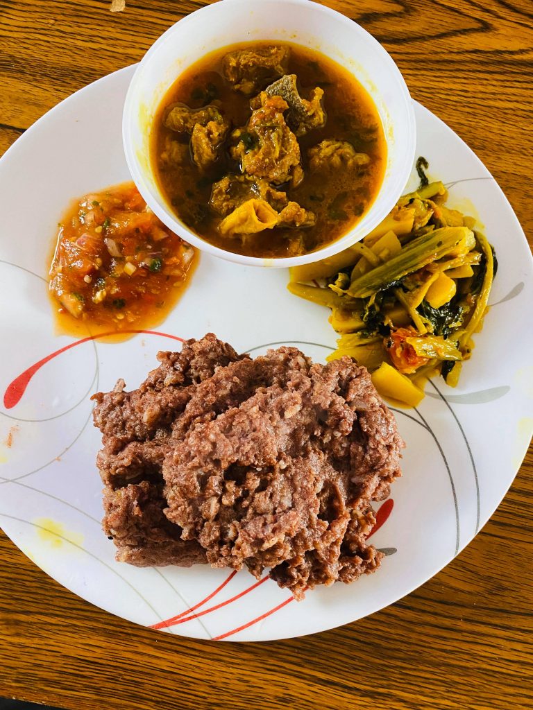 A bowl of soup sitting on a plate of vegetables, sauce and a Bhaji