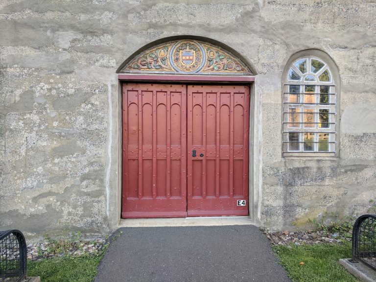 Red door with Mercer ceramic tiles on concrete wall.