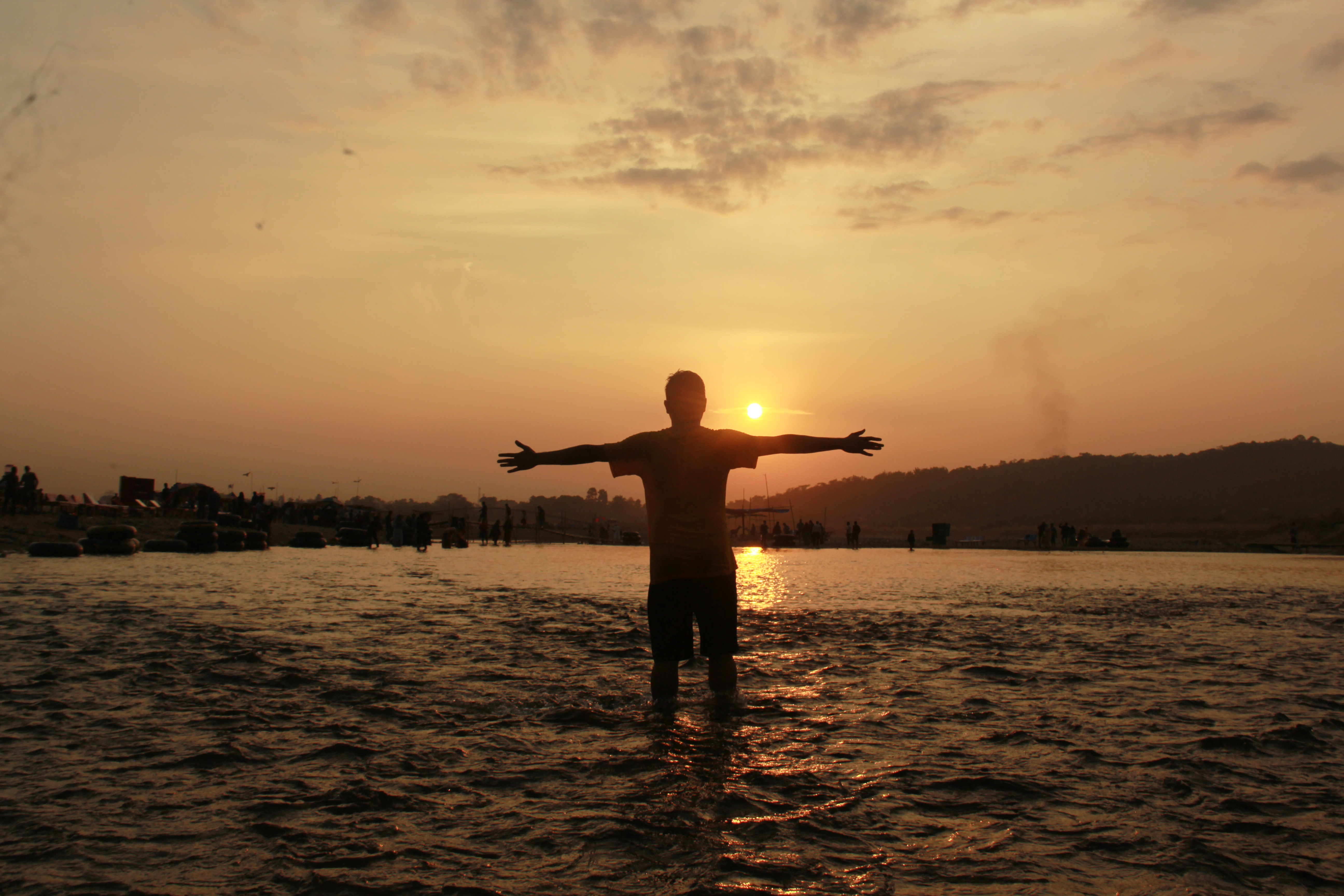 a man standing in water with arms out in the air