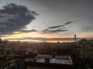 Dawn, distant sunrise on the horizon beyond the city rooftops.  