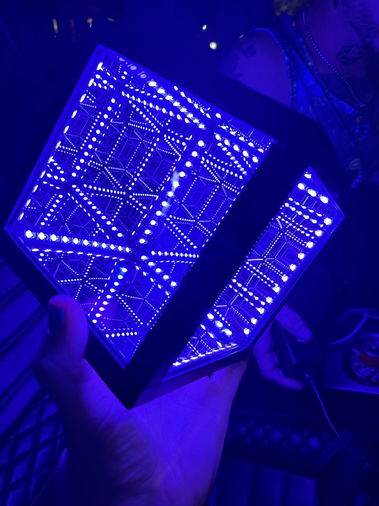 An illuminated hypercube in the palm of a hand