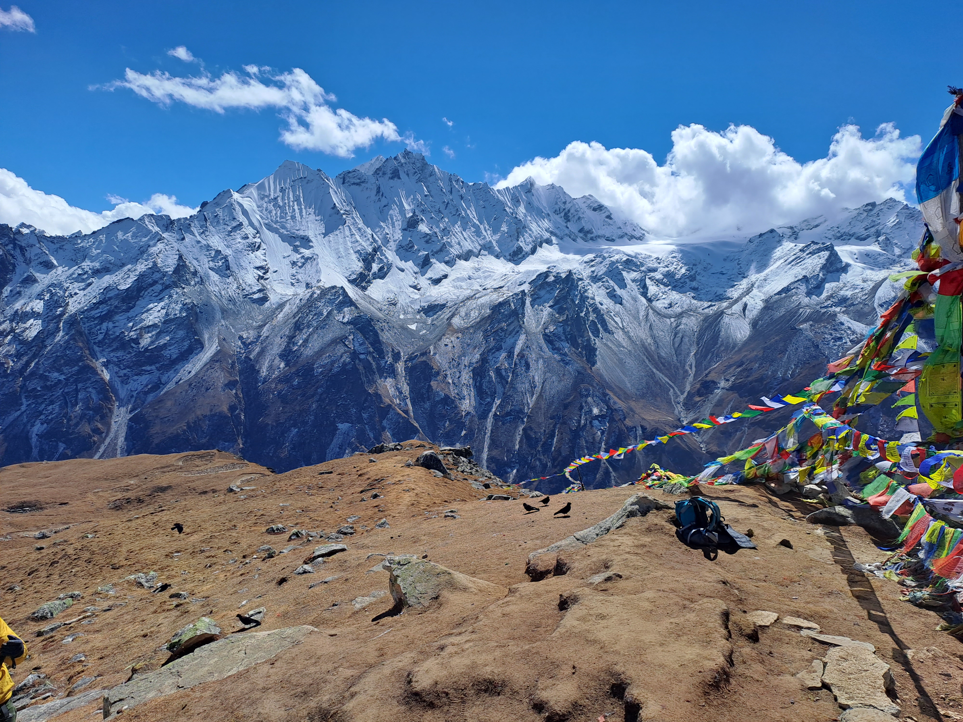 The view of mountains with a blue sky and prayer flags as seen from Langtang.