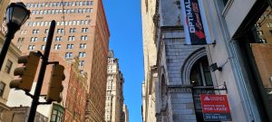 Buildings on either side with blue sky above. Walnut Street Facing West looking up at the sky.
