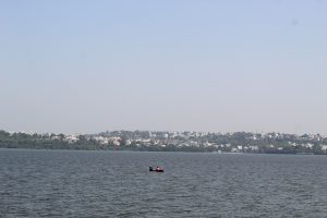 A city surrounded by lake and a boat in the middle of the lake. 