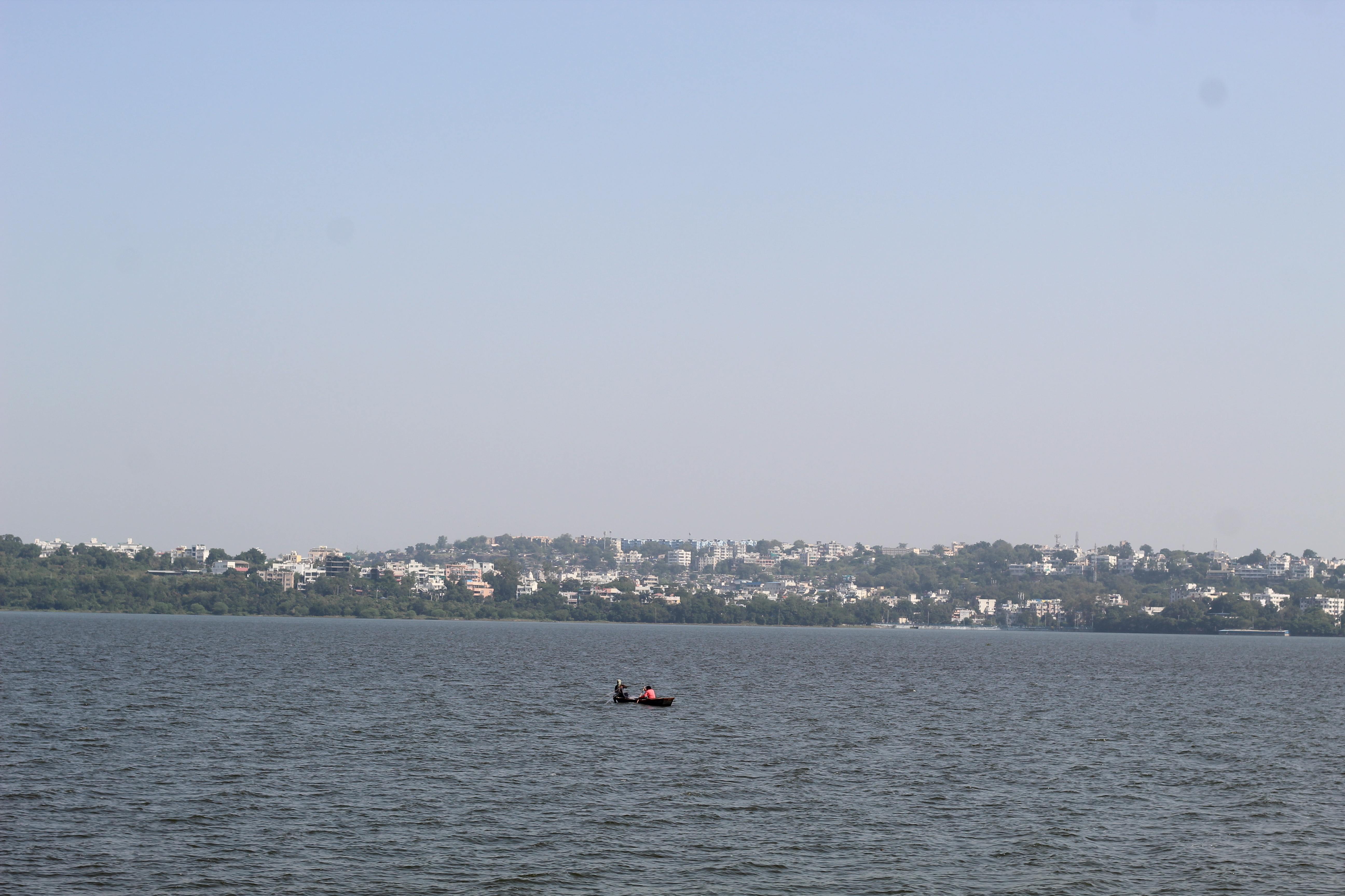 A city surrounded by lake and a boat in the middle of the lake. 