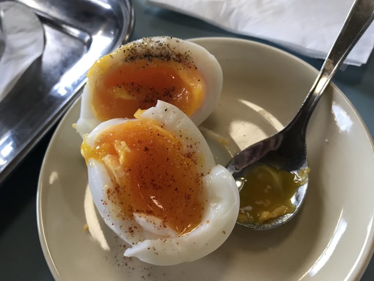 A soft-boiled egg cut in half, in a plate with a spoon. Viennese breakfast