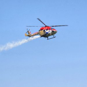 Helicopter flying in the blue sky which has a peacock printed on that.