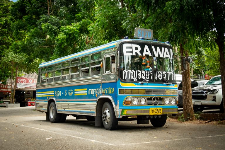 A colorful public transportation bus parked near the Erawan waterfalls in Thailand.