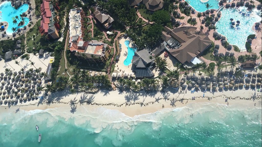 A beach resort in Punta Cana, Dominican Republic, as seen from a helicopter including the ocean, beach, hotels, and swimming pools