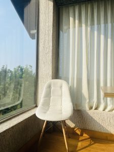 A white chair placed in front of a window in the sunlight. 