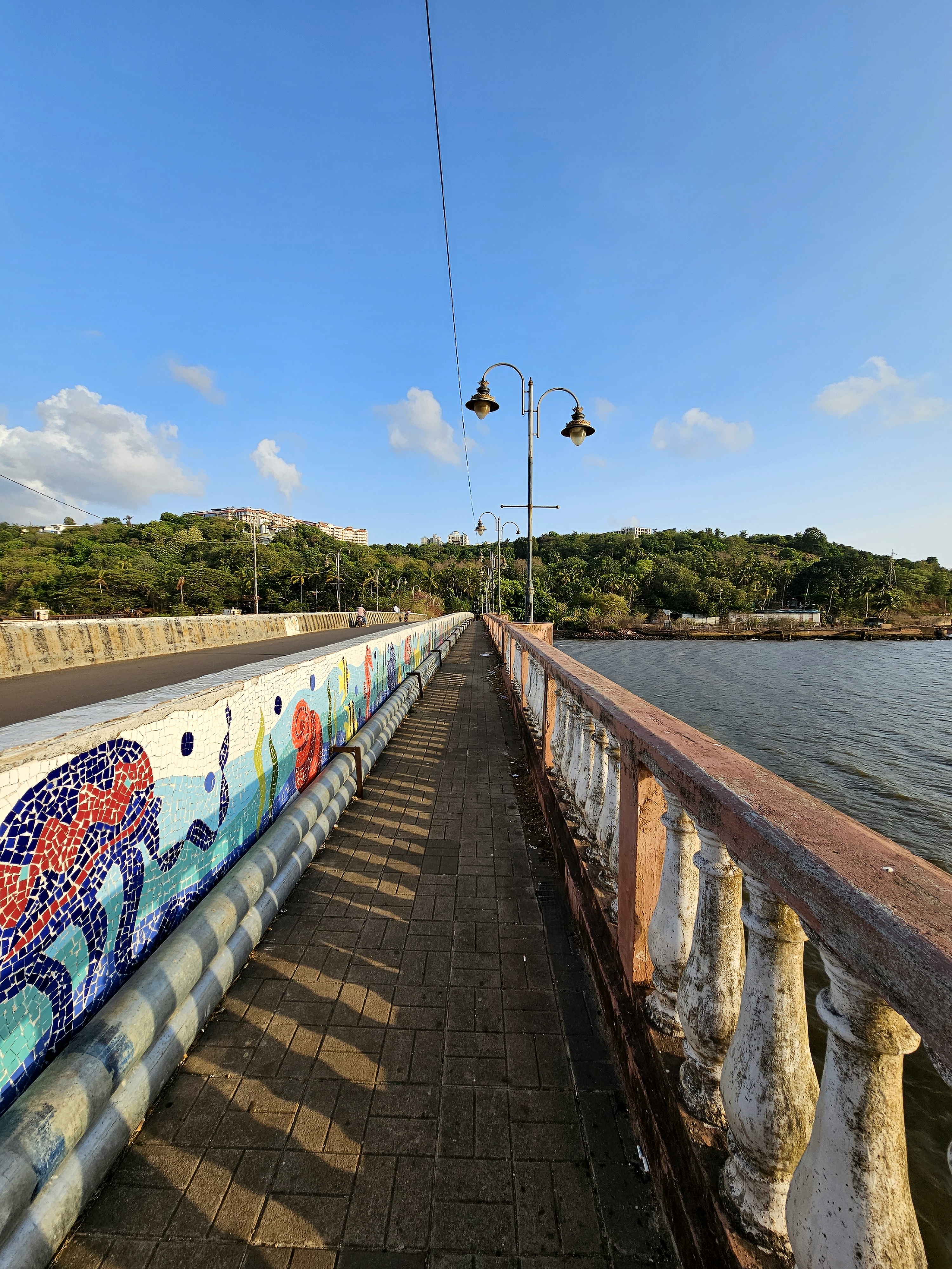 Walkway on the side of a bridge with artworks on the side of the separation in Goa. 