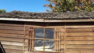 Upper half of an old wooden shed with wood shingles
