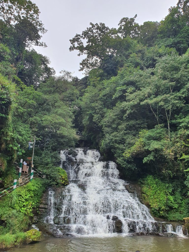 Beautiful waterfall on hill, stairs on the left.