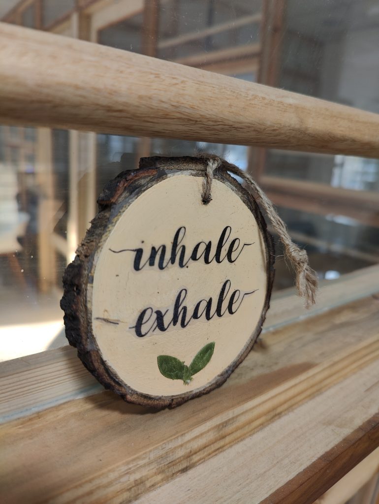 Wooden Engraving that says “Inhale, Exhale” and leaf