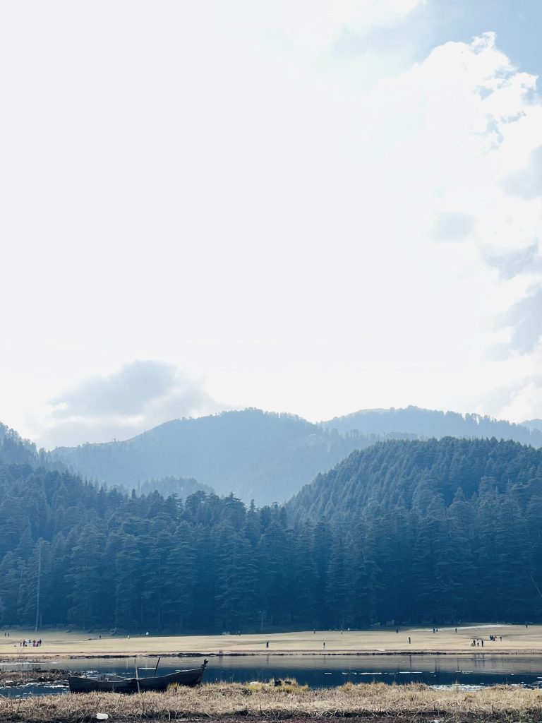 A view of the lake with mountains and sky in the background on a cold day.