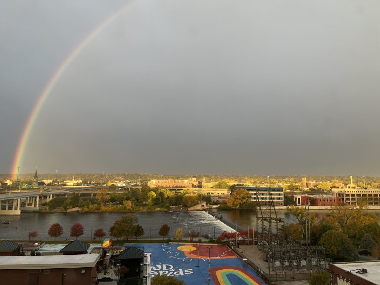 Rainbow over Grand Rapids Michigan, dark skies filled with storm behind.