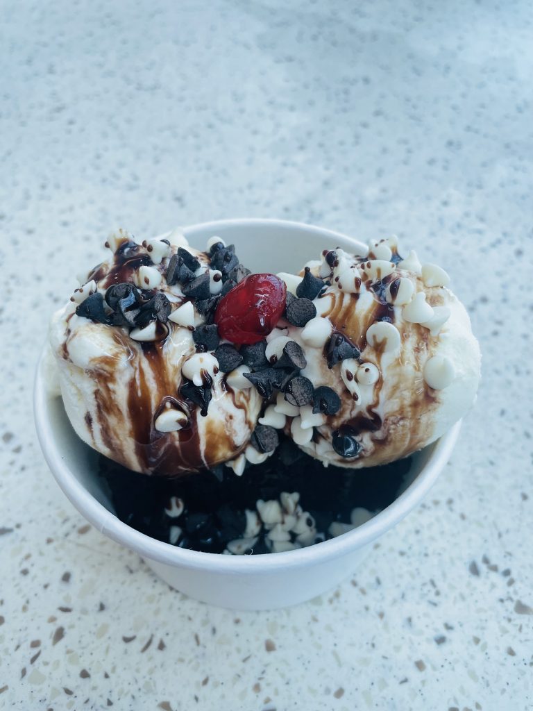 Chocolate brownie with two scoops of vanilla ice cream topping with milk and white chocolate chips