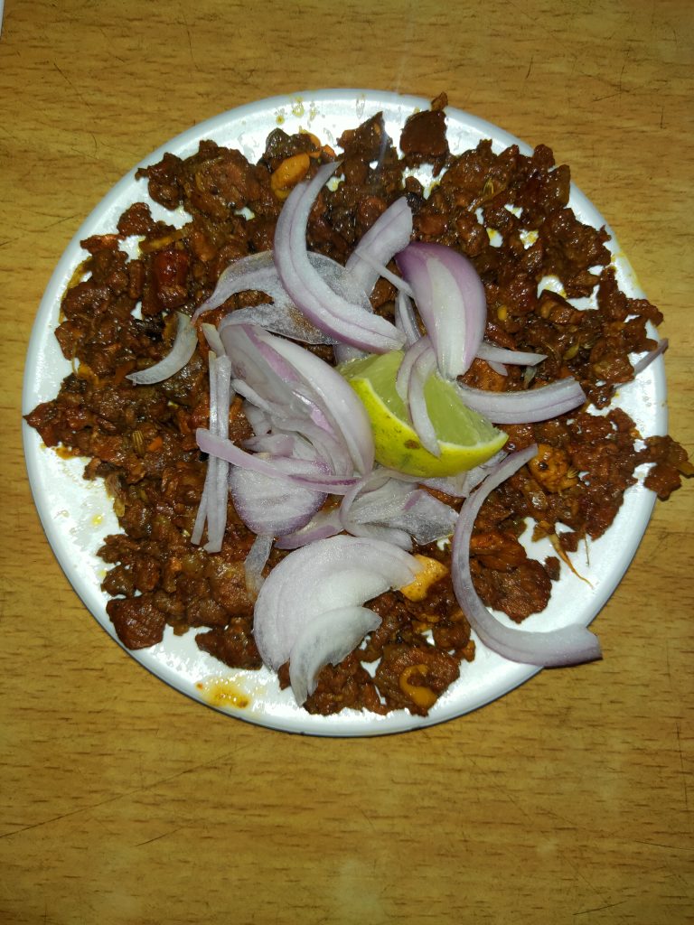 Beef chili with onions on a white plate