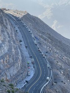 A highway up the side of a mountain with cars along the road and parked at the parking lot at the top. #WPPhotoFestival