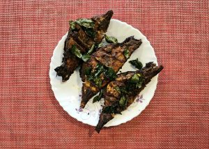 Grilled fish topped in Kerala style with green spices on a white plate 