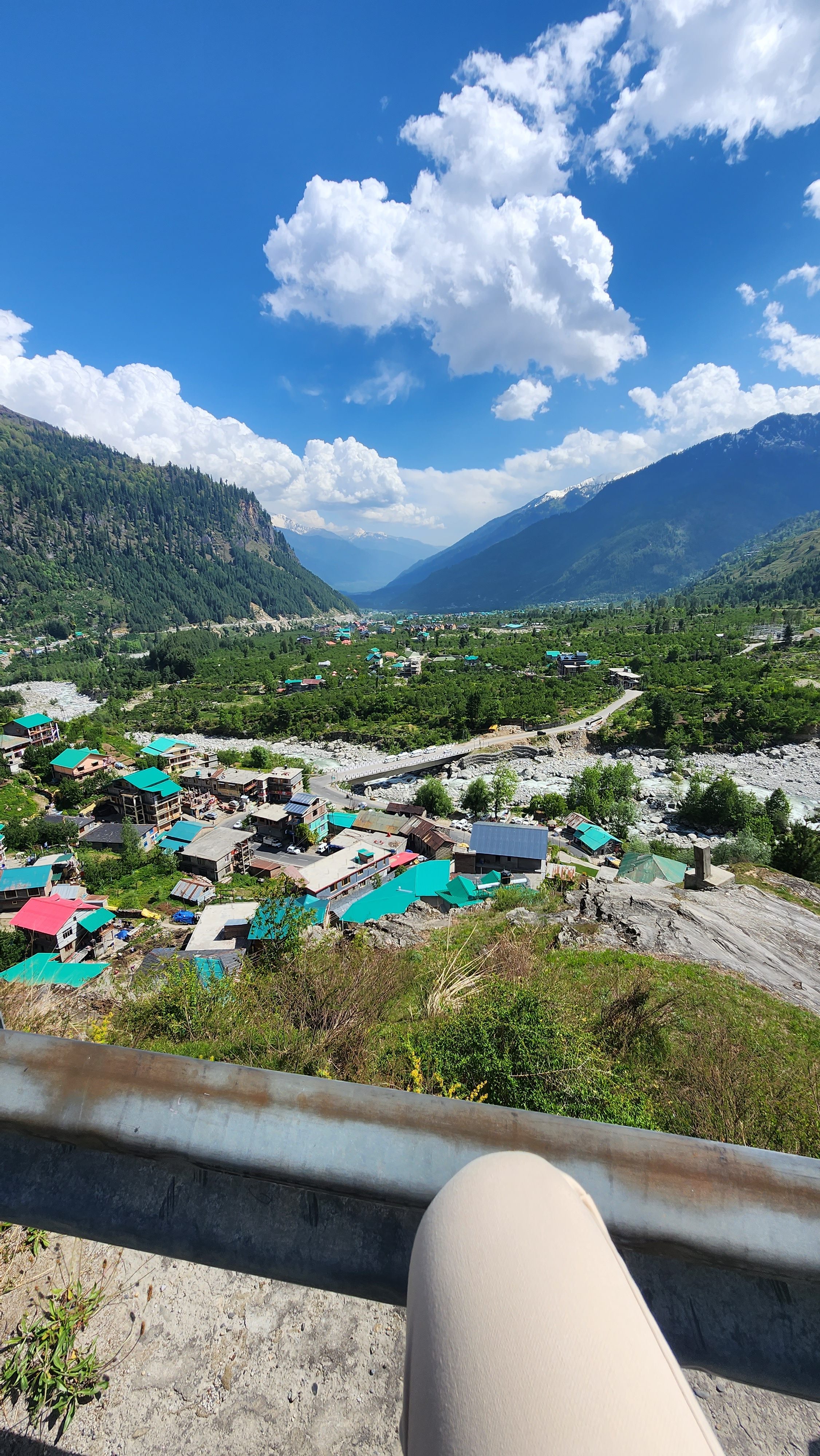 In this picture, there are mountains, some clouds in the sky, and houses where people live.