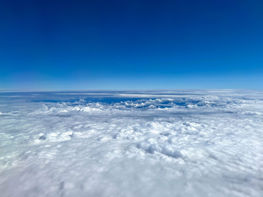 A bright blue sky above white fluffy clouds as seen from above.