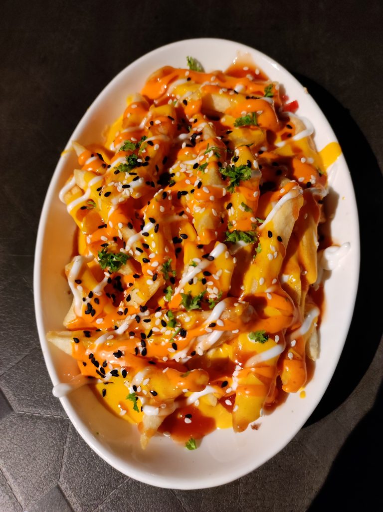 A plate of french fries with cheese, sesame seeds, sauce and parsley.
#WPPhotoFestival