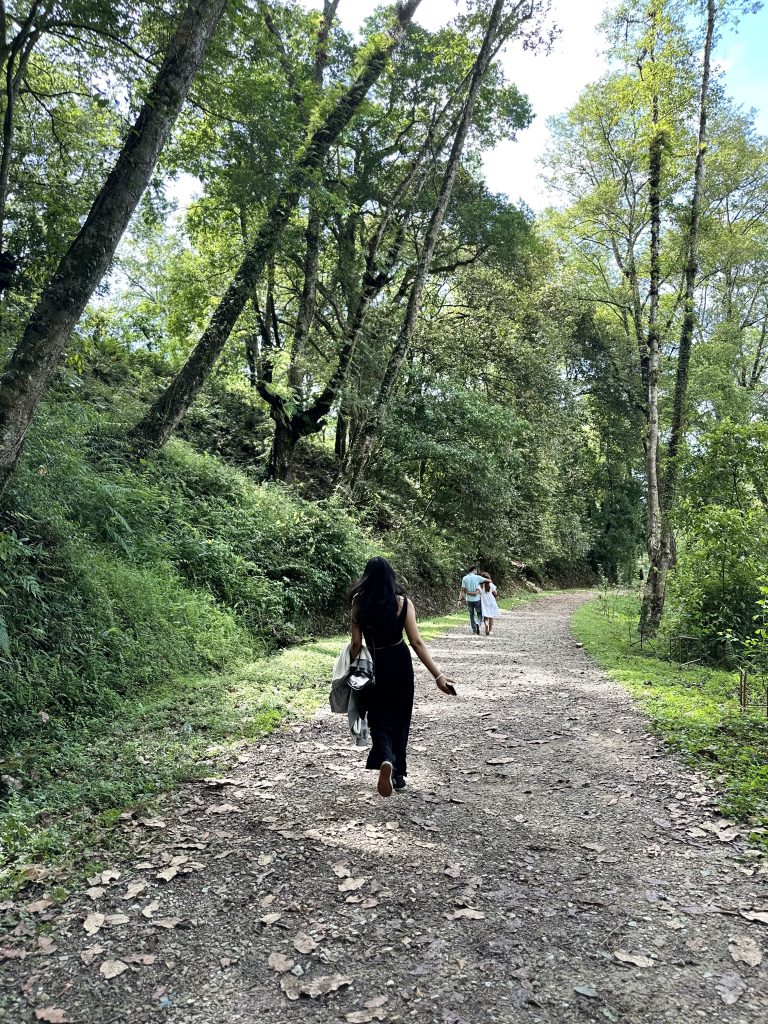 A girl is walking in a park and she is following a couple in front of her.