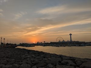 Sunset on a beach with buildings and ferris wheel in the background. 