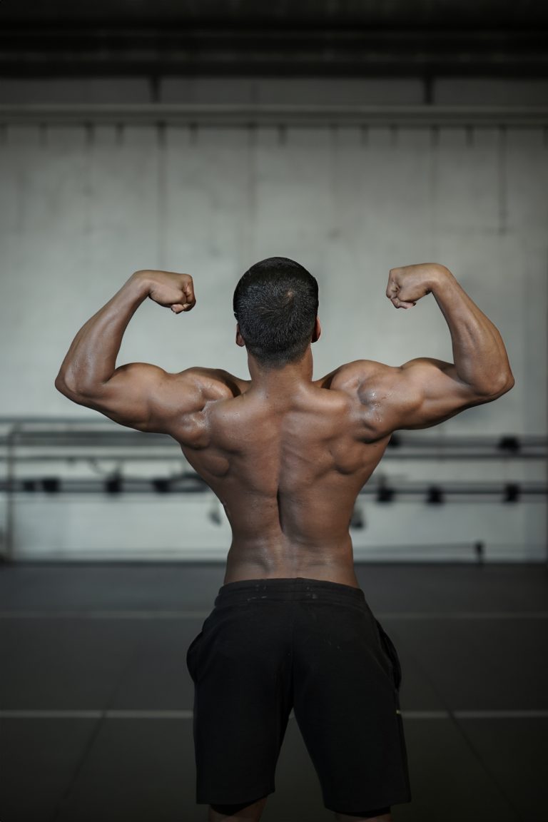 Man, seen from behind, flexing large muscles.